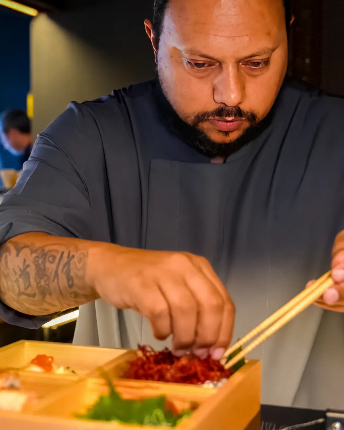 Júnior Machado finaliza com pauzinhos um bento em caixa de madeira