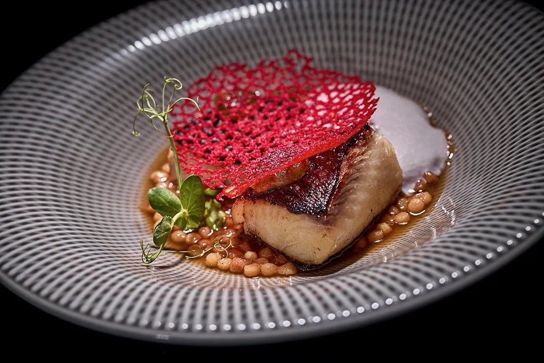 Pescado con teja roja sobre legumbres
